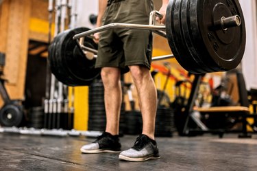 close-up shot of a man doing a trap bar deadlift in the gym