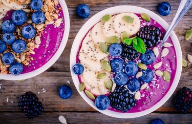 Breakfast Recipes for Longevity Açai Berry Bowl in a white bowl with a spoon and blueberries, blackberries and bananas