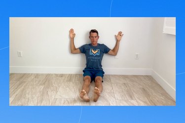 physical therapist grayson wickham demonstrating the wall slide exercise on a blue background