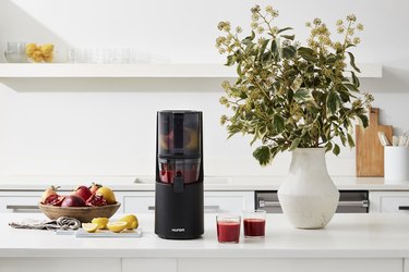 hurom juicer on counter with fruits and juice