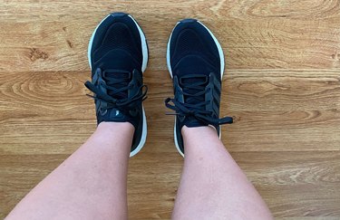 a close-up of the author wearing black Adidas Ultraboost 22 running shoes on wood floor