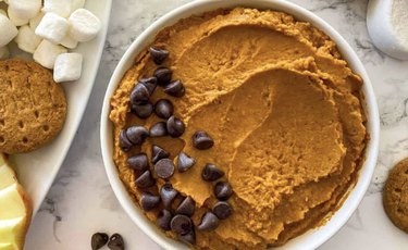A close up of pumpkin spice hummus with chocolate chips and other toppings