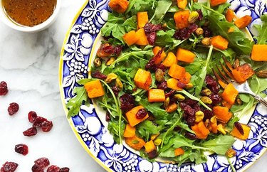 Roasted Butternut Squash Salad in bowl with blue trim fruit design on marble tabletop