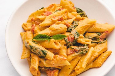 Instant pot penne pasta in creamy sauce on a white plate.