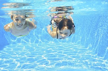Kids swim underwater in pool