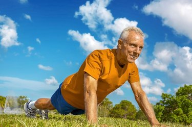 Determined senior man doing pushup exercise on meadow