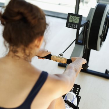 Rear view of a young woman exercising on a rowing machine at the gymnasium