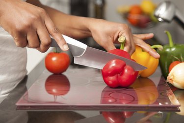 African  American womans hand slicing a red pepper