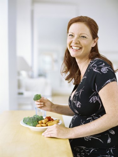 side profile of a pregnant person with long red hair smiling and looking up