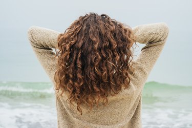 Curly brunette in a sweater on the coast