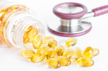Fish oil capsules spilling out of a bottle and stethoscope