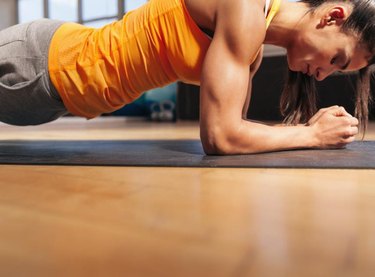 Cropped shot of woman exercising in the gym. Muscular female doing core workout on fitness mat with copy space.
