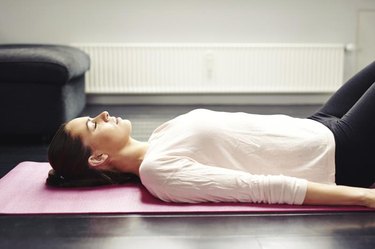 Image of fit young woman relaxing on yoga mat. Female lying on floor - Savasana