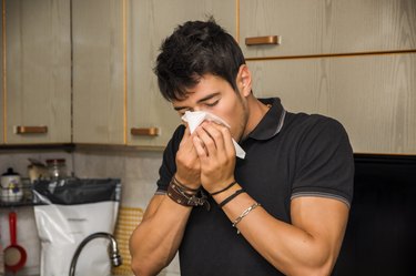 Young Man Blowing Nose into Tissue