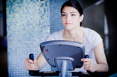 Woman riding an exercise bike in gym.Cardio and fat loss