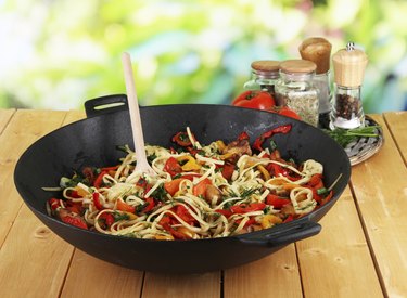 Noodles with vegetables in wok on nature background