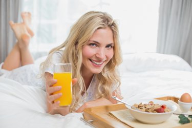 Happy young woman having breakfast in bed