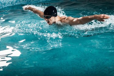 Muscular young man swims the butterfly in the pool