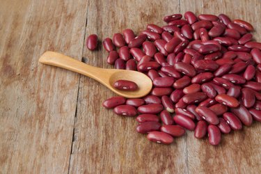 Dried red beans and wooden spoon on wooden background