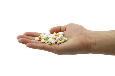 Man holding heap of different pills in the hand