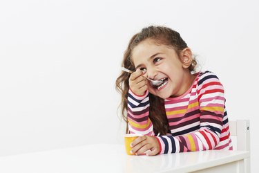 Young girl eating yoghurt in studio