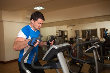 Man exercising on elliptical machine in gym