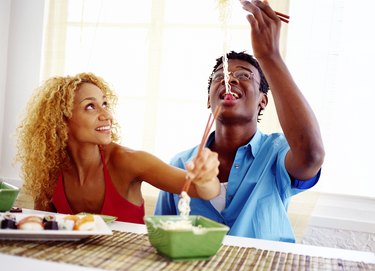 view of a young couple eating Chinese food with chopsticks