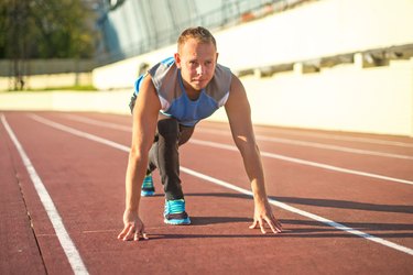 Athletic man standing in  posture ready to run on treadmill.