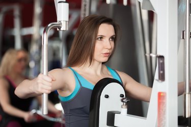 Girl exhales while doing exercises with weights on training appa