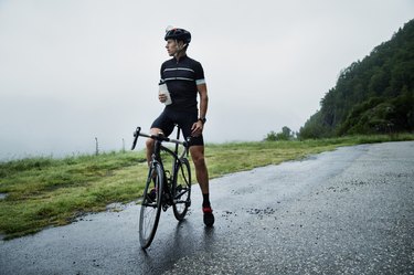 Male race cyclist resting by mountain road