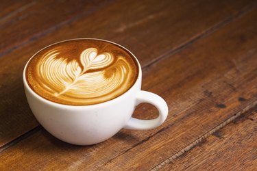 Latte art, coffee on the wooden desk as background.