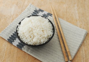 White rice in black bowl with wood chopsticks