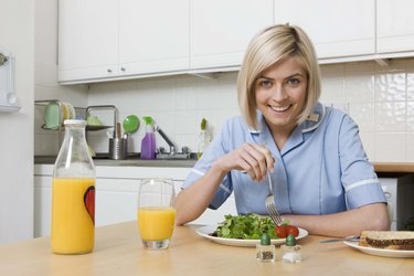 Woman eating salad with orange juice