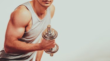 Strong fit man exercising with dumbbells.
