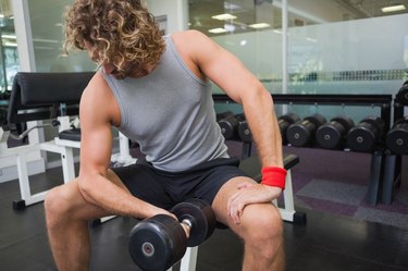 Young man exercising with dumbbell in gym