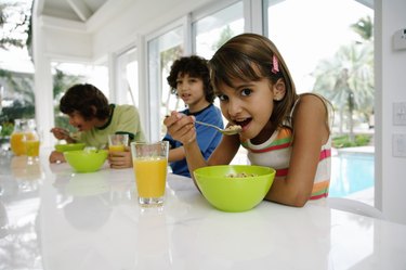 Three kids (8-10) at table, having breakfast, portrait