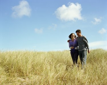 Mature couple walking through grass, smiling