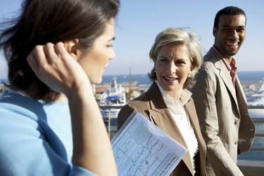 Two businesswomen and man by sea, smiling