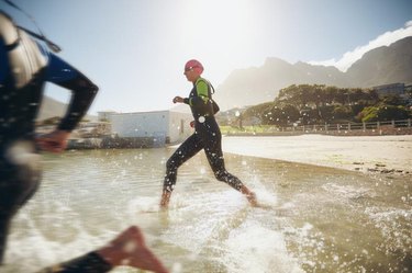 Participants running into the water for start of a triathlon. Two triathletes rushing into water.