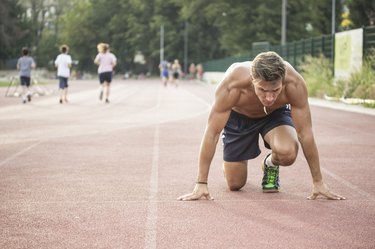 Sprinter at start position, kneeling, muscular body.