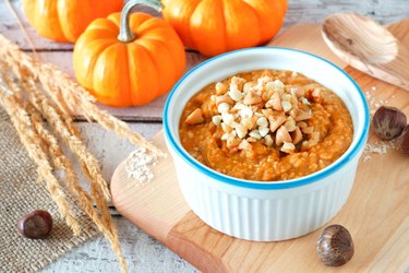 Table scene with bowl of autumn pumpkin oatmeal
