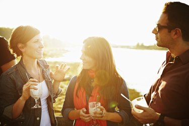 Group of three friends standing on dock at sunset