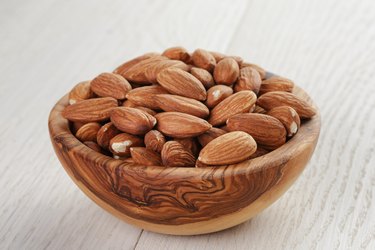 roasted almonds in bowl on white wooden table