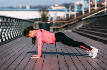 Beautiful fitness woman doing push ups during outdoor training workout.