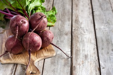 red beets on a wooden cutting board on top of a wooden table