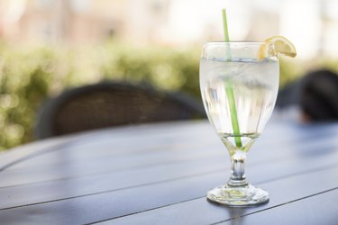 Glass of Iced Water with Lemon sits on Outside Table