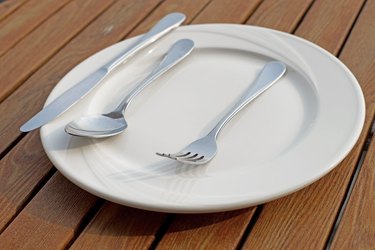 spoon fork and knife on empty white plate