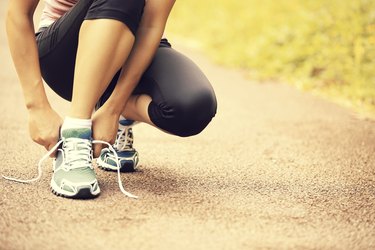 woman runner tying shoelaces on trail