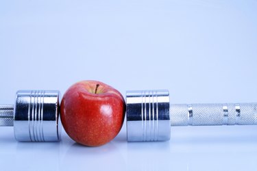 Close up of apple between dumbbells