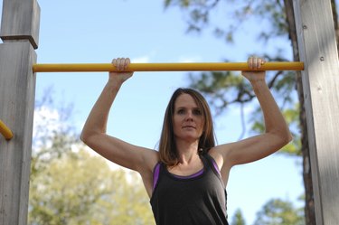 young stong woman doing pull ups outdoors